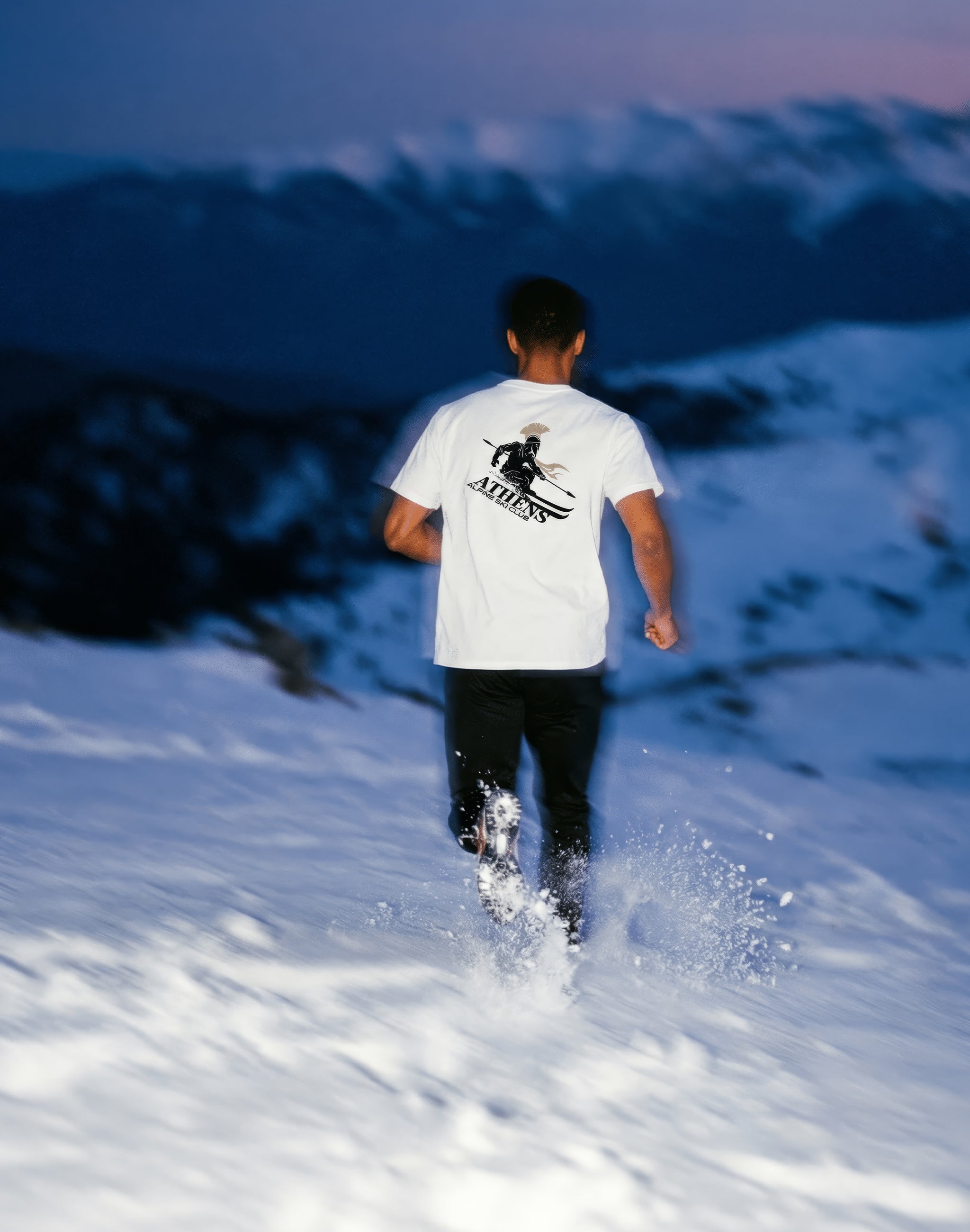 Athens Alpine Ski Club white t-shirt worn by male model running on ski mountain — PERAMA Sports Federation