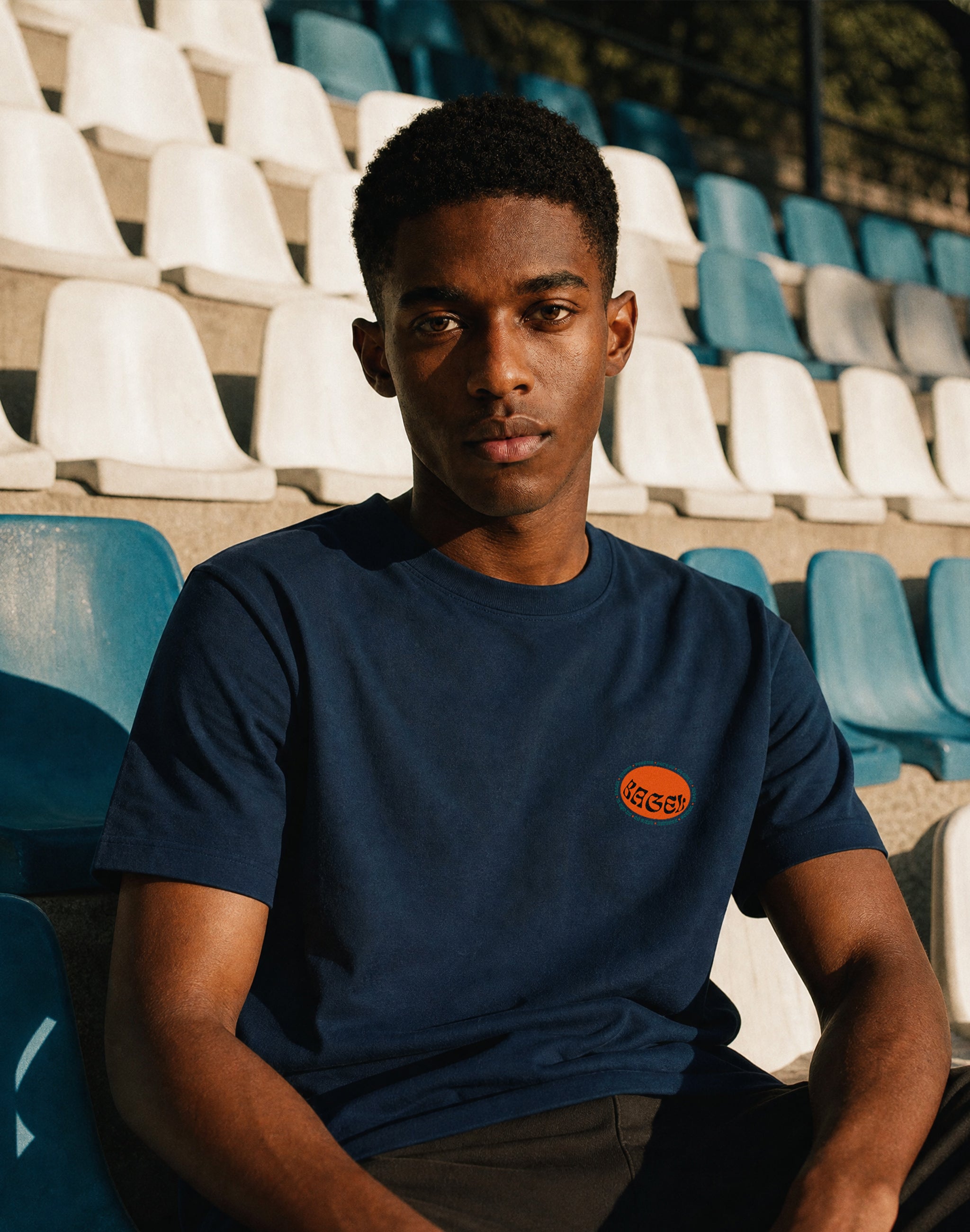 Bagel t-shirt worn by male model at empty stadium midday sun — PERAMA Classics