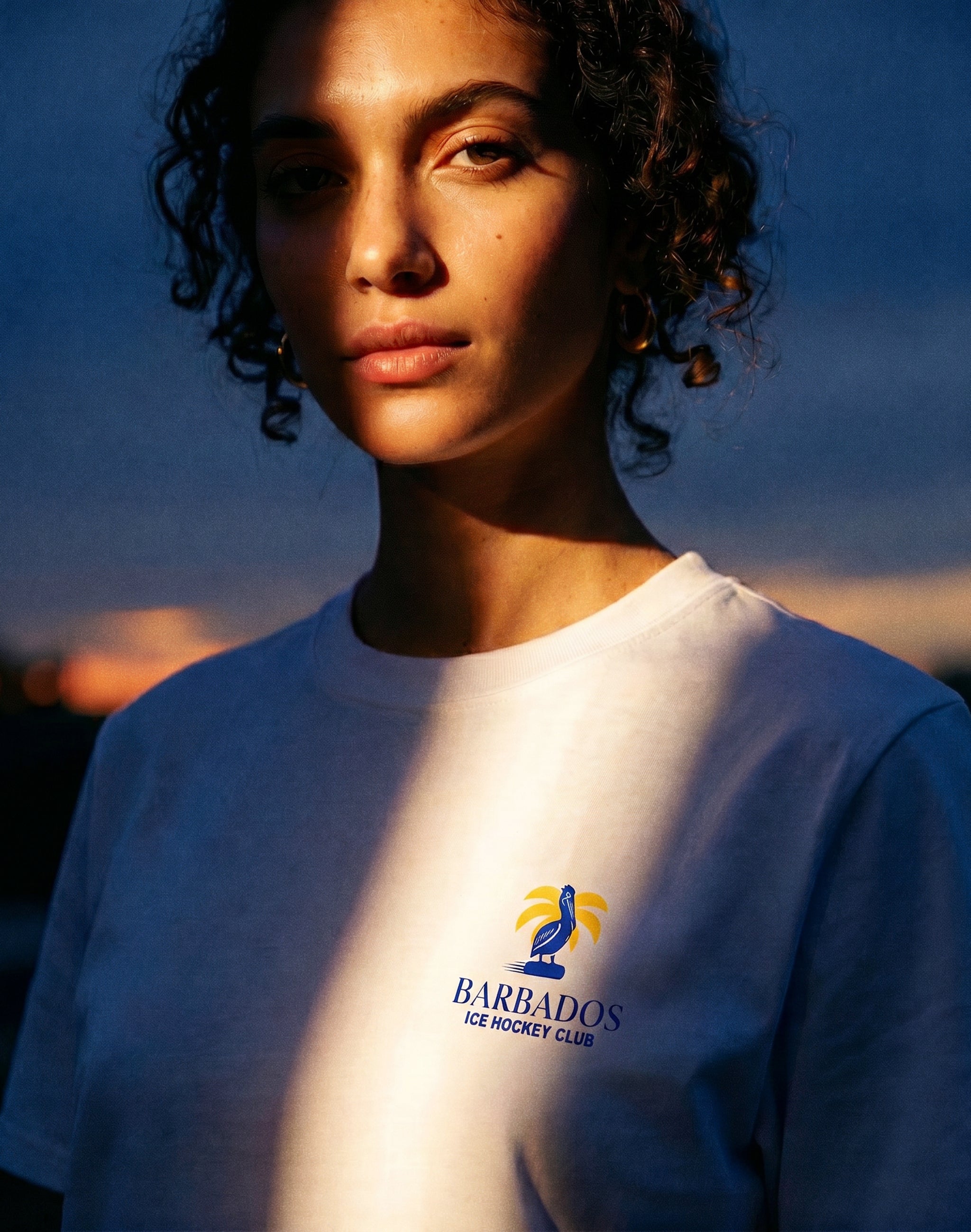 Barbados Ice Hockey Club white chest print worn by female model at dusk — PERAMA Sports Federations