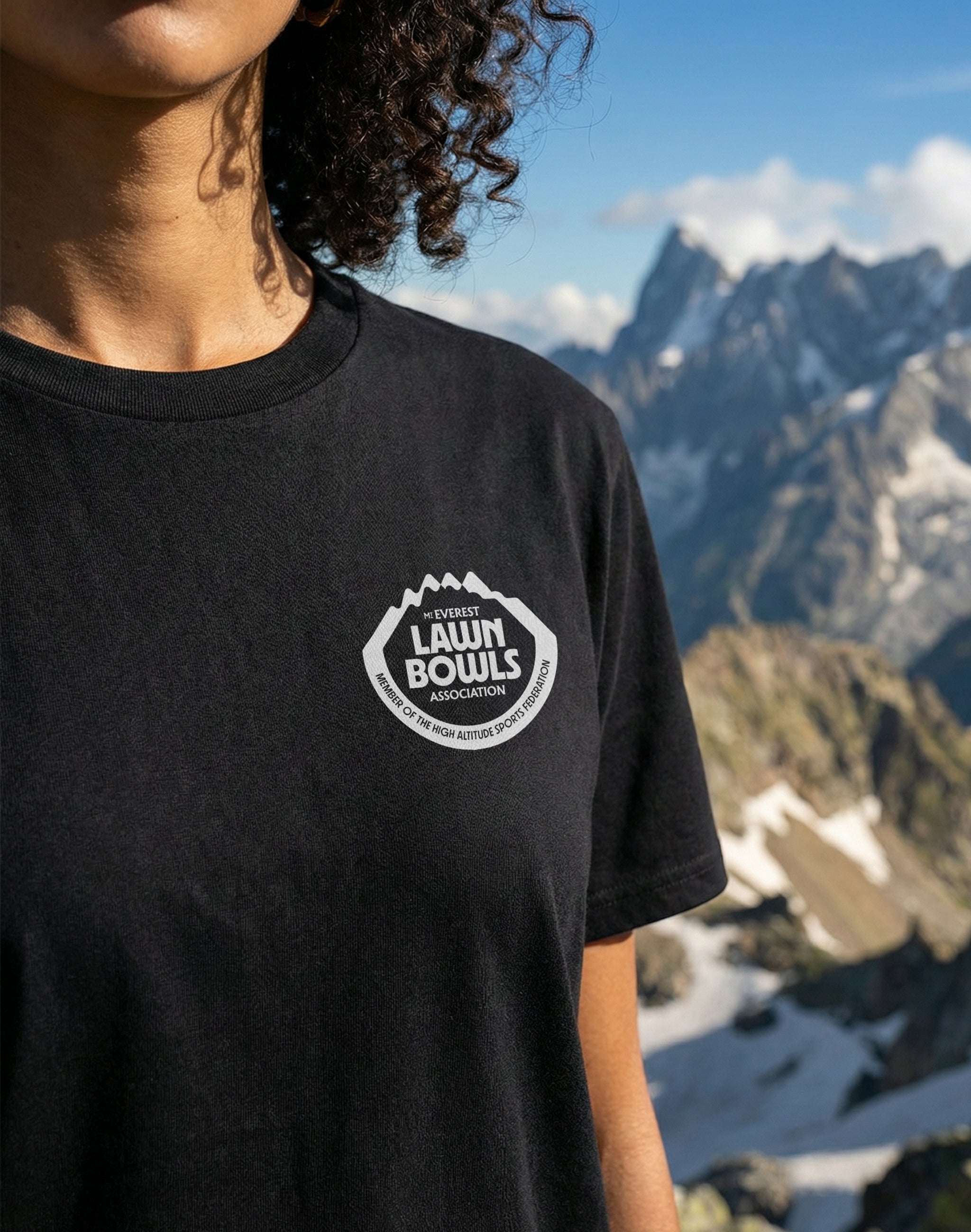 Mt Everest Lawn Bowls Association Uniform T-Shirt black front chest print close up with model standing with mountains as a backdrop — PERAMA Federations