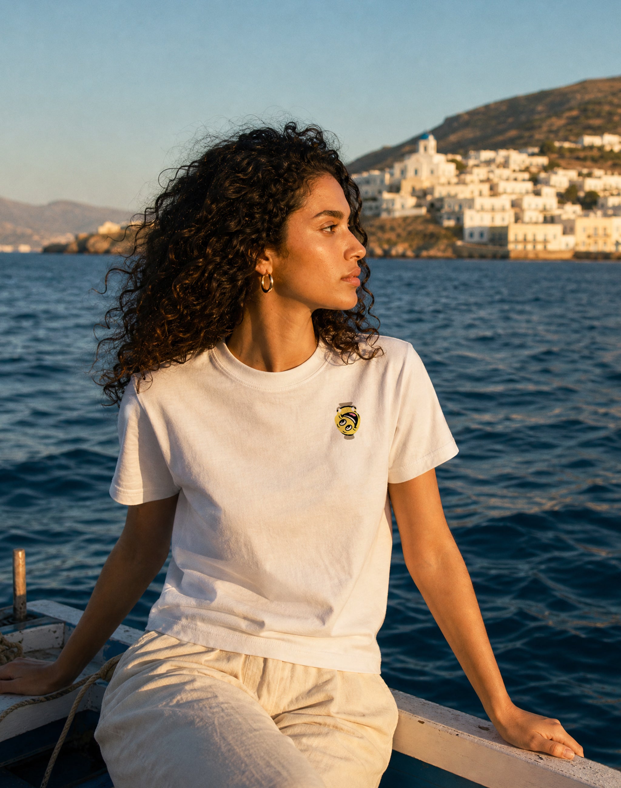 Amphora 07 T-Shirt white front print worn by female model on small fishing boat off a greek island — PERAMA Odyssey