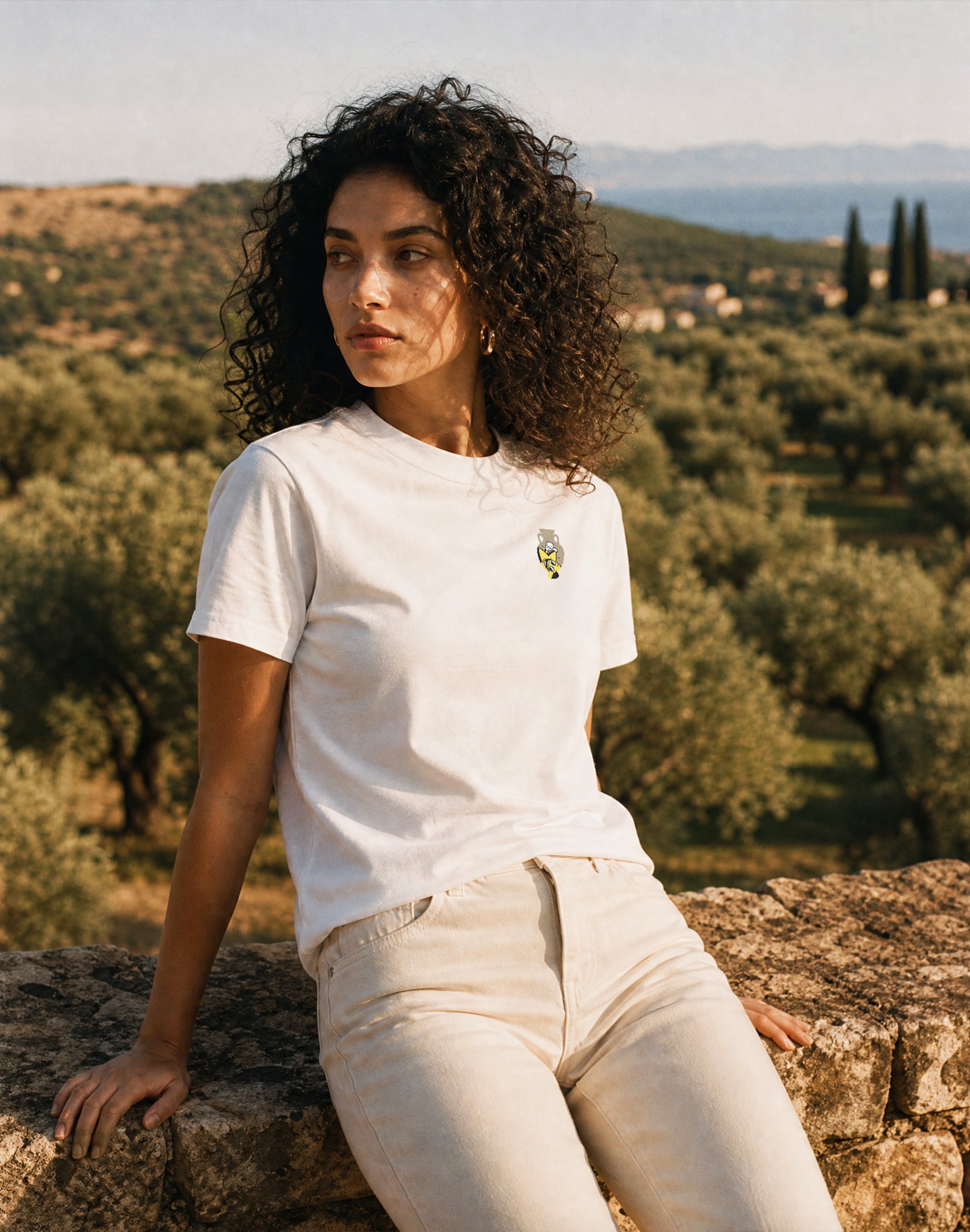 Amphora 09 Superstar white T-shirt worn by female model on
Greek coast — PERAMA Odyssey