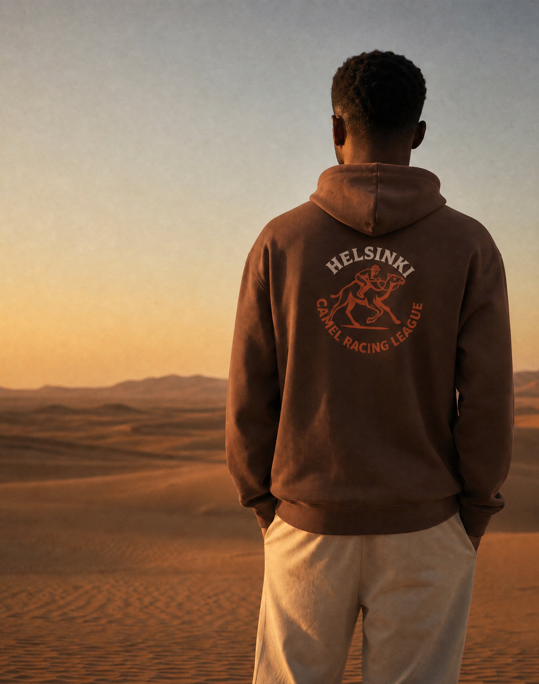 Helsinki Camel Racing League heritage clay hoodie worn by
male model in desert landscape — PERAMA Federations