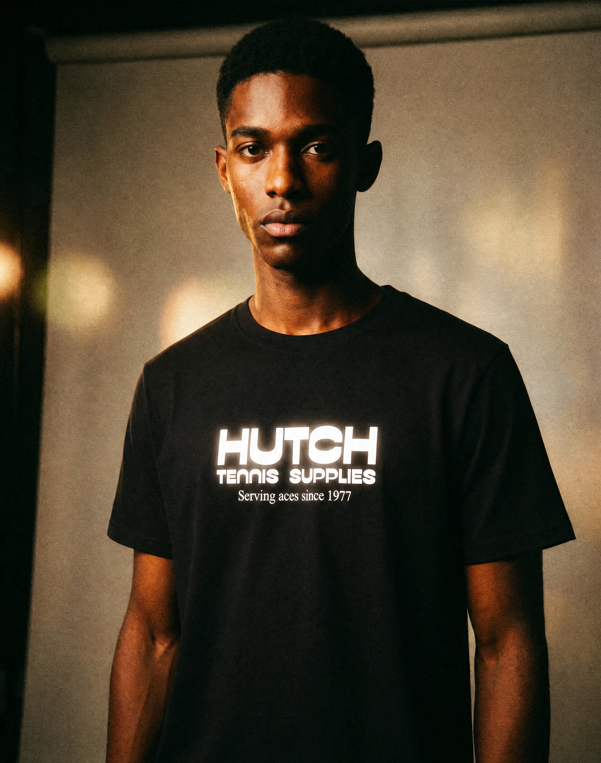 Hutch Tennis Supplies T-Shirt black middle chest print sponsor worn by male model in studio — PERAMA Sponsors