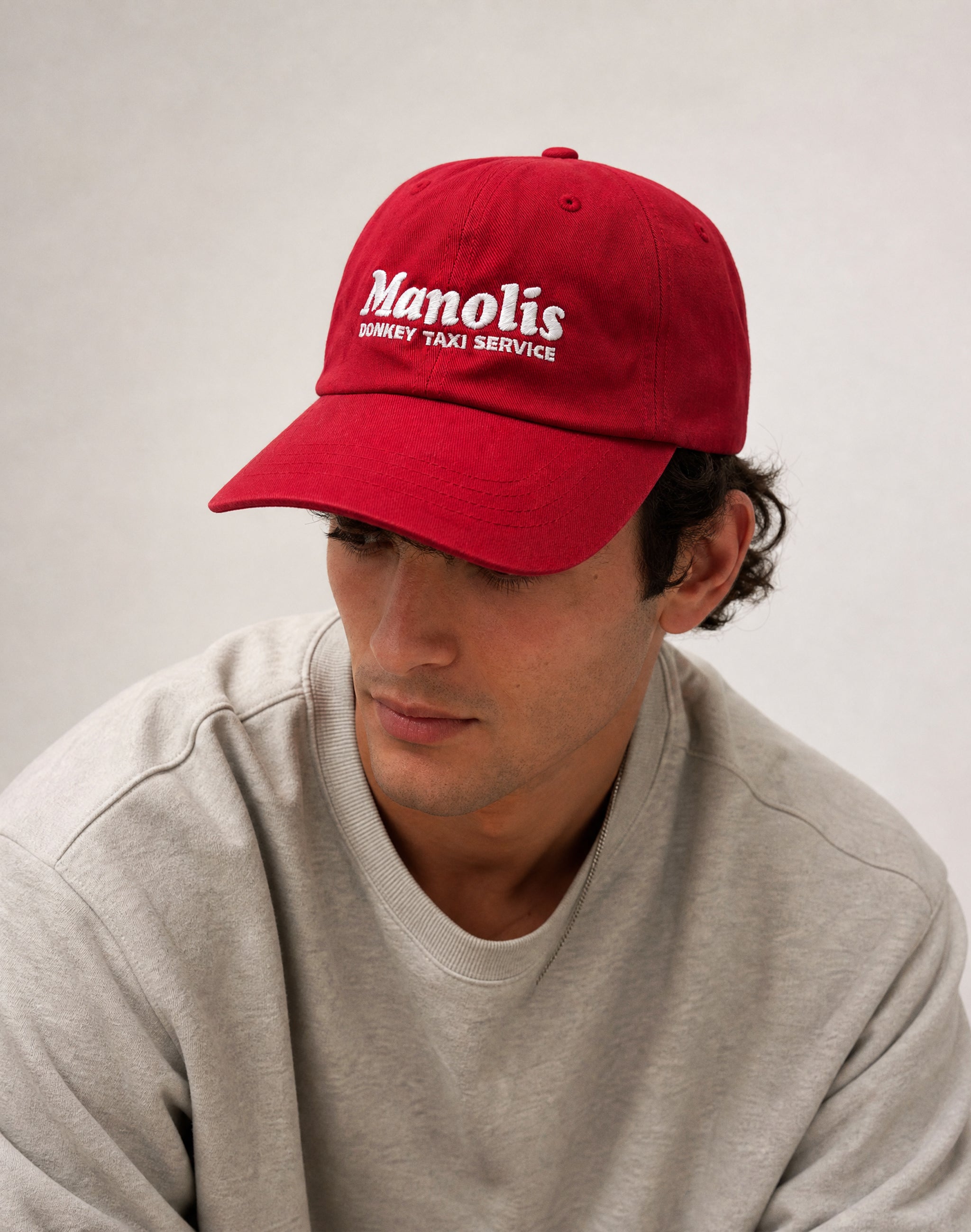 Manolis Donkey Taxi Service cranberry red cap embroidered worn by male model in studio— PERAMA Sponsors