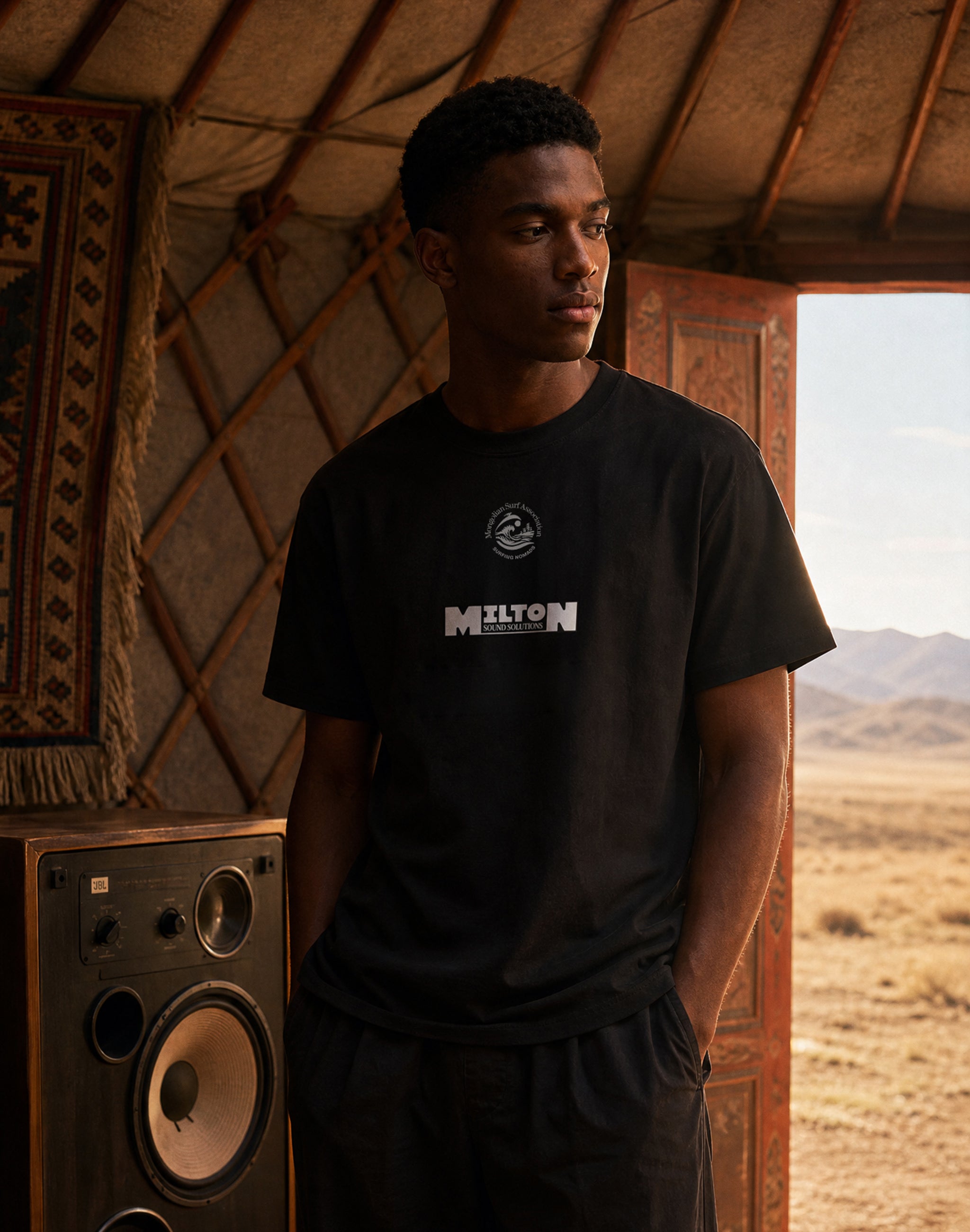 Mongolian Surf Association black tournament t-shirt front, Milton Sound Solutions sponsor worn by male model in a yurt in Mongolia with vintage speakers — PERAMA Federations